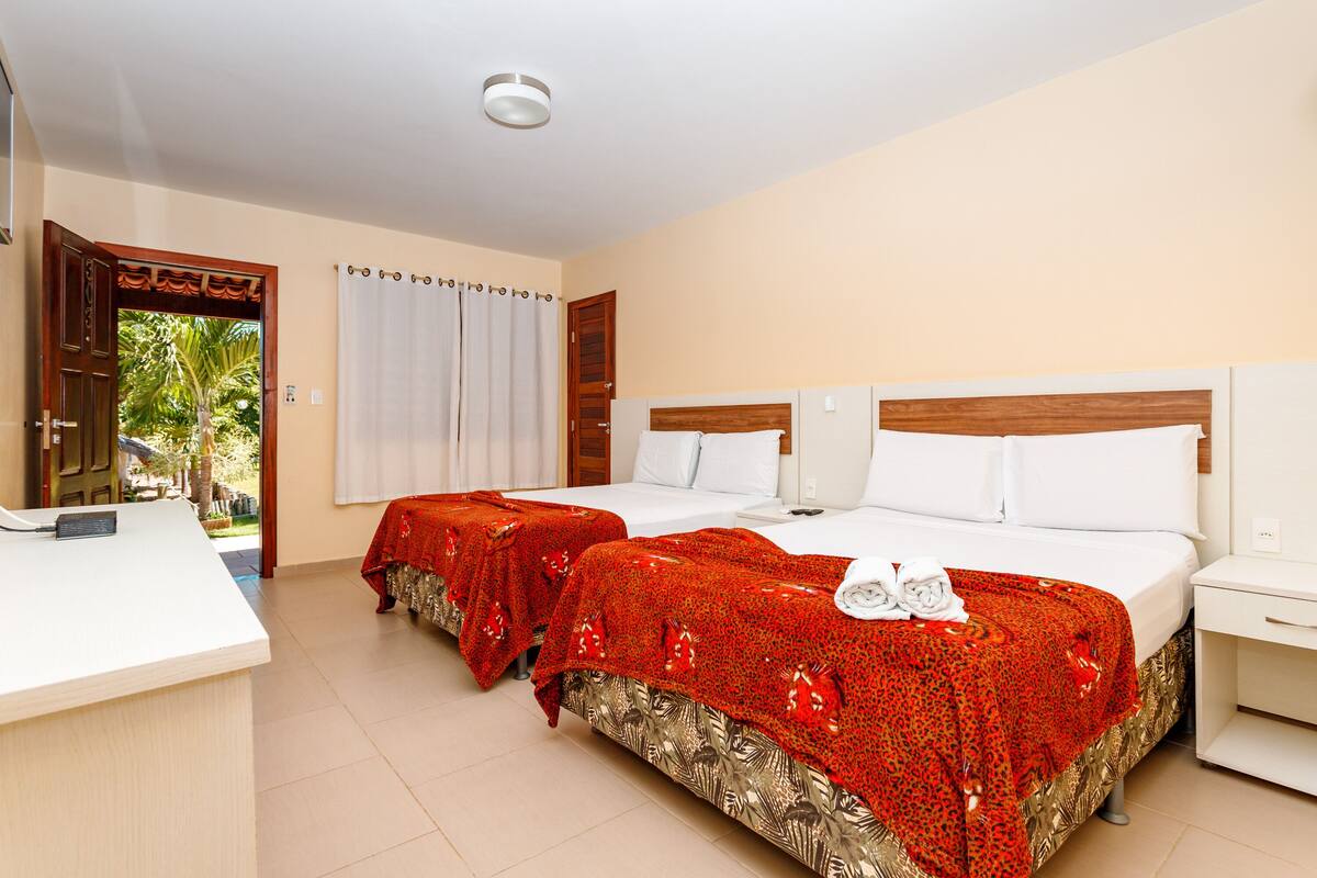 A hotel room with two beds, a reception desk, and a view of the outdoors.