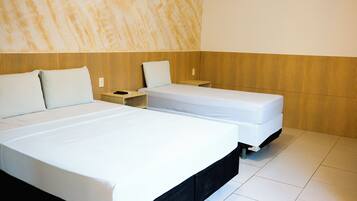 A hotel room with two beds, a wooden headboard, a nightstand, and a white tiled floor.