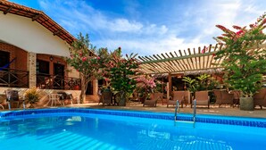 A swimming pool with lounge chairs and a covered patio area. - Pousada Jardim dos Orixás (Aracati)