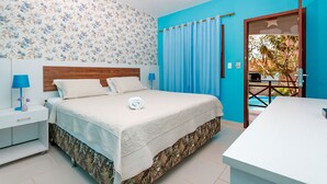 A bedroom with a bed, nightstands, a desk, a window with curtains, and a view of a pool. - Pousada Jardim dos Orixás (Aracati)