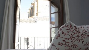 A bedroom with a view of a building through a window. - Hotel La Ciudad (Ronda)