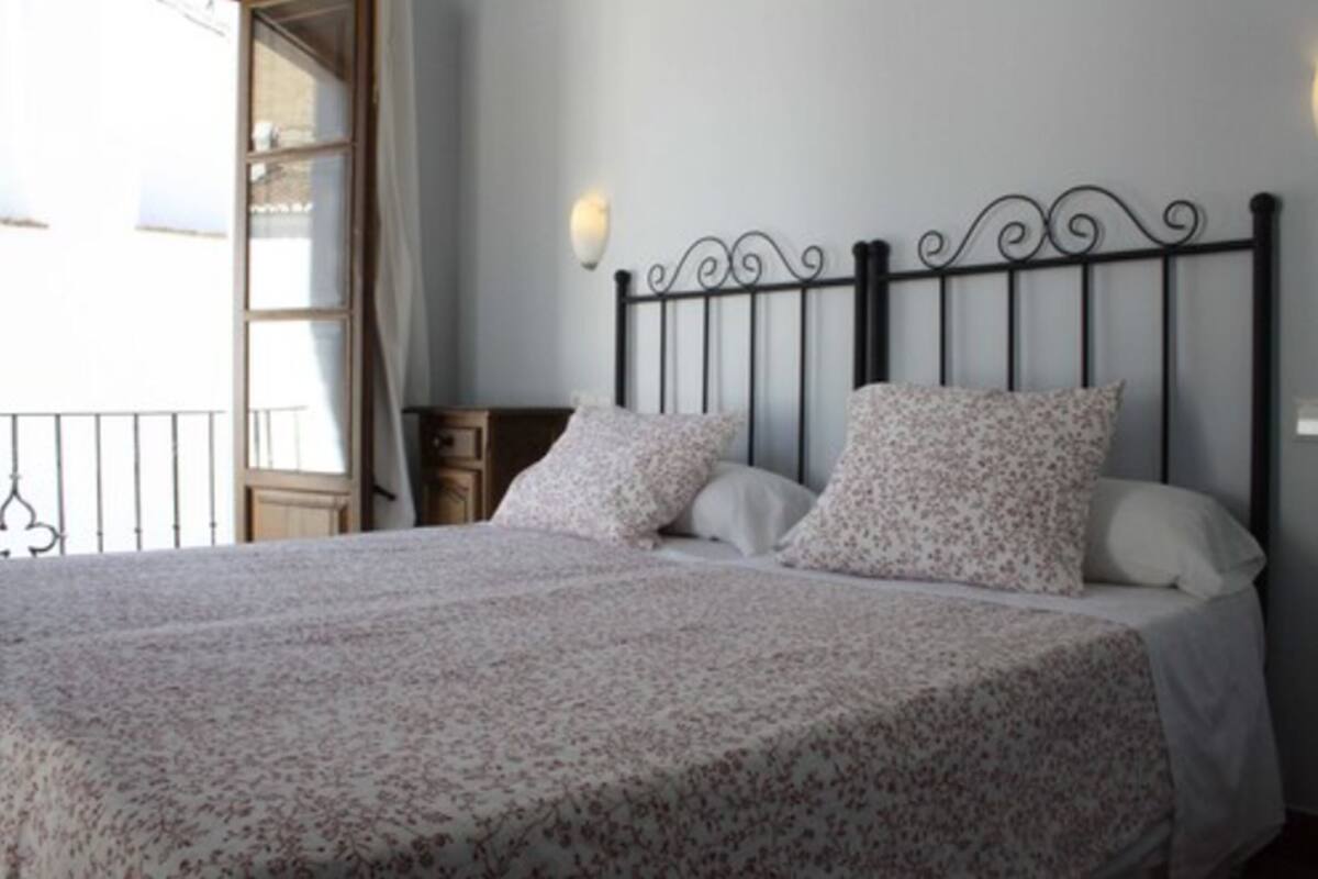 A bedroom with a bed, floral bedding, a black metal headboard, and a nightstand.