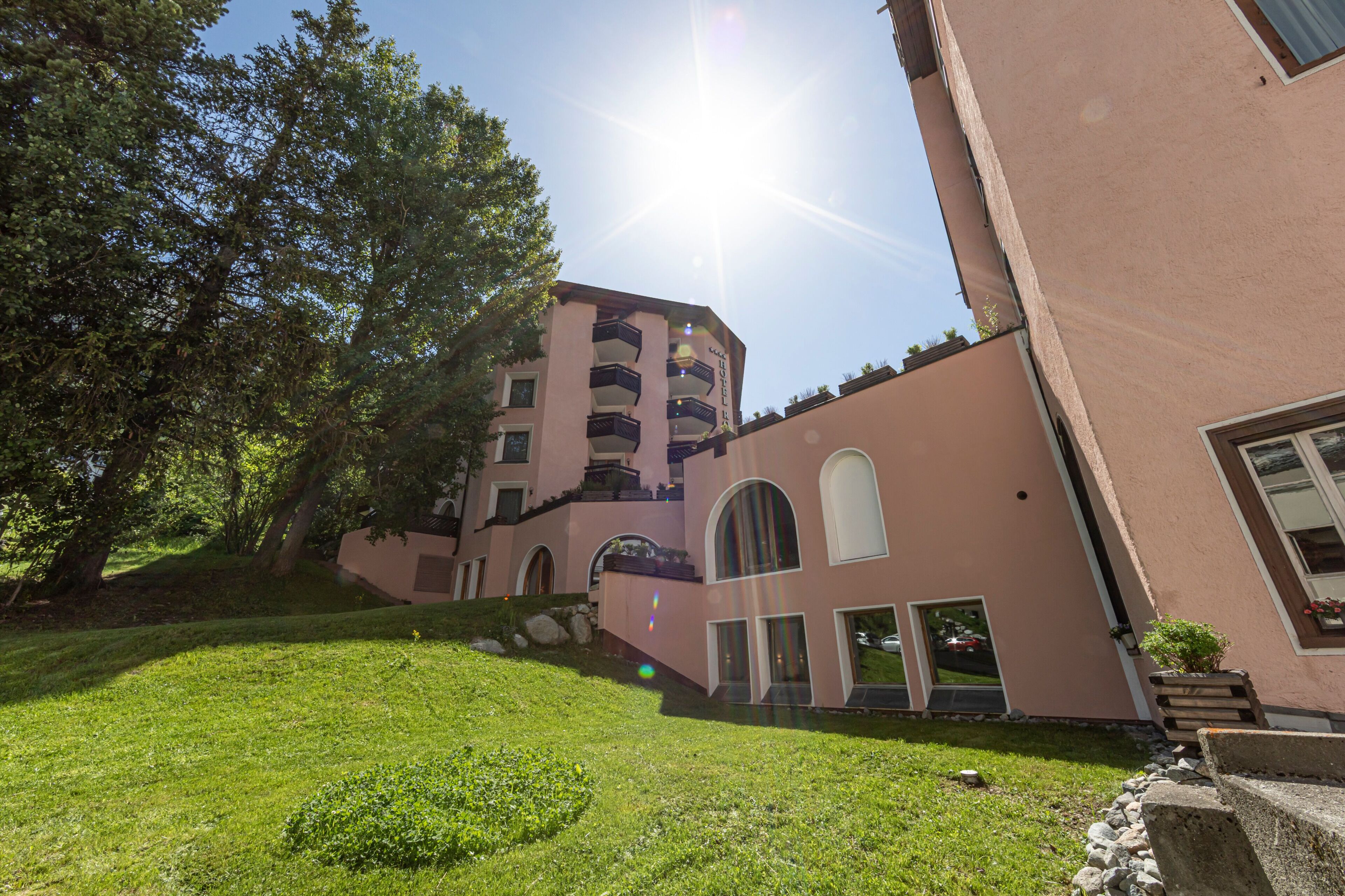 Un edificio con fachada rosa, ventanas arqueadas y una escalera que conduce a un nivel superior.