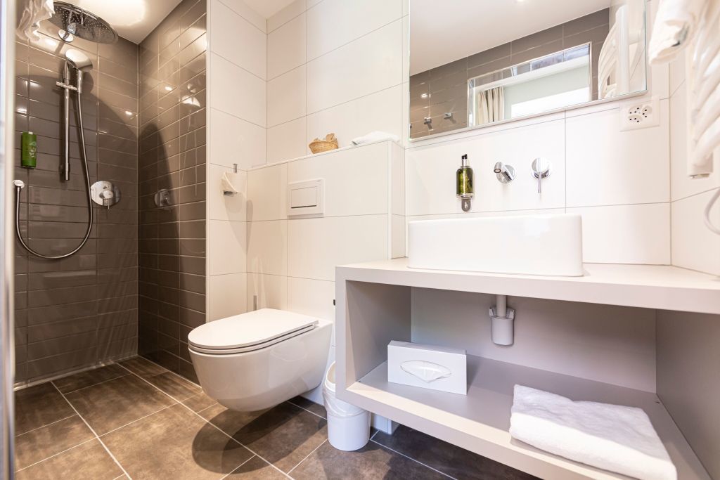 A modern bathroom with a shower, toilet, and a vanity with a mirror and towel rack.