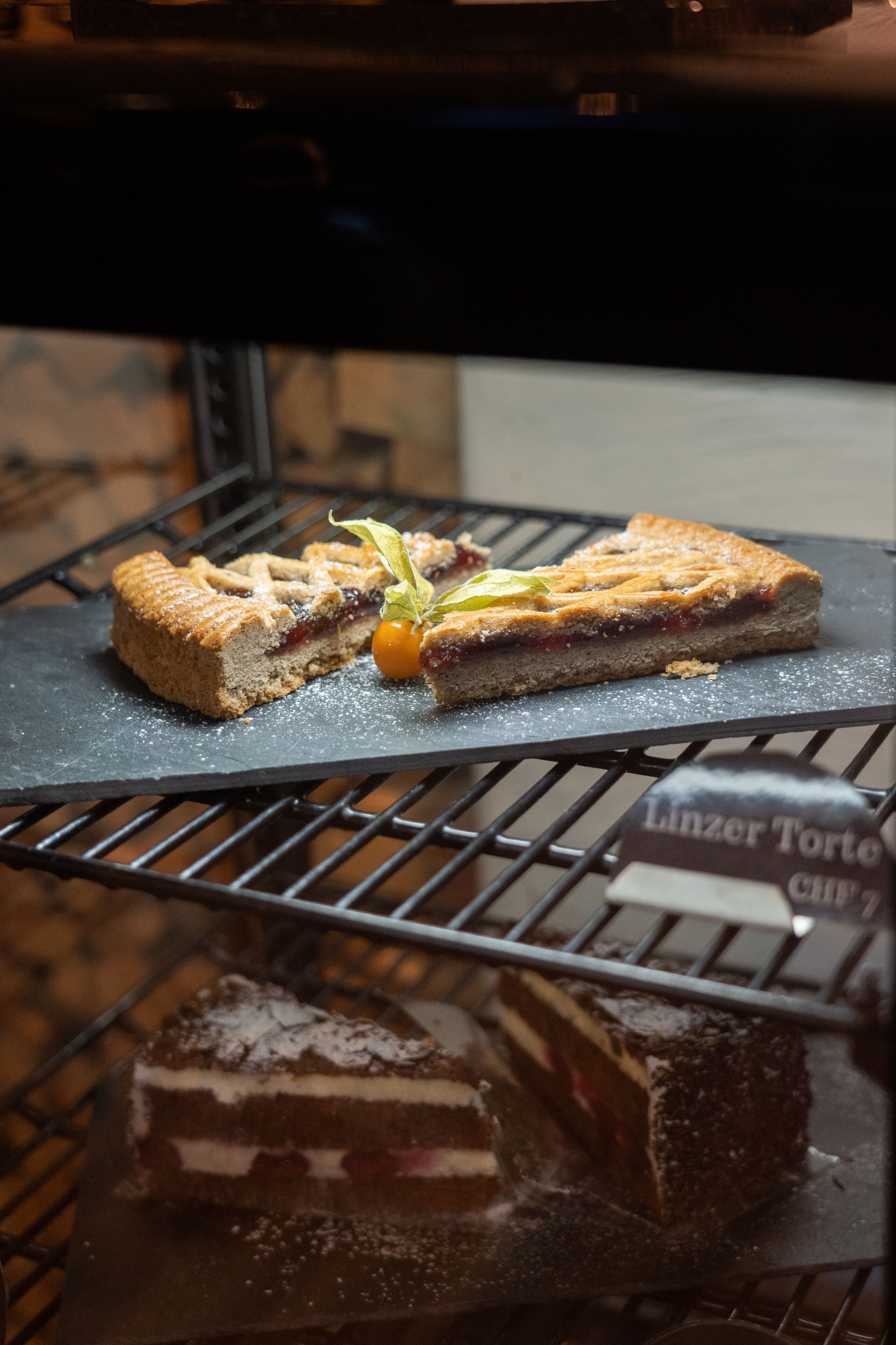 Una presentación de postres con una rebanada de pastel y una tarta sobre una rejilla de metal.