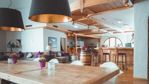 A modern kitchen with wooden beams, a large wooden table, and white chairs. - Hotel Rosatsch - Stammhaus (Pontresina)