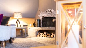 A cozy room with a wooden ceiling, a fireplace, a lantern, and a table with a lamp. - Hotel Rosatsch - Stammhaus (Pontresina)