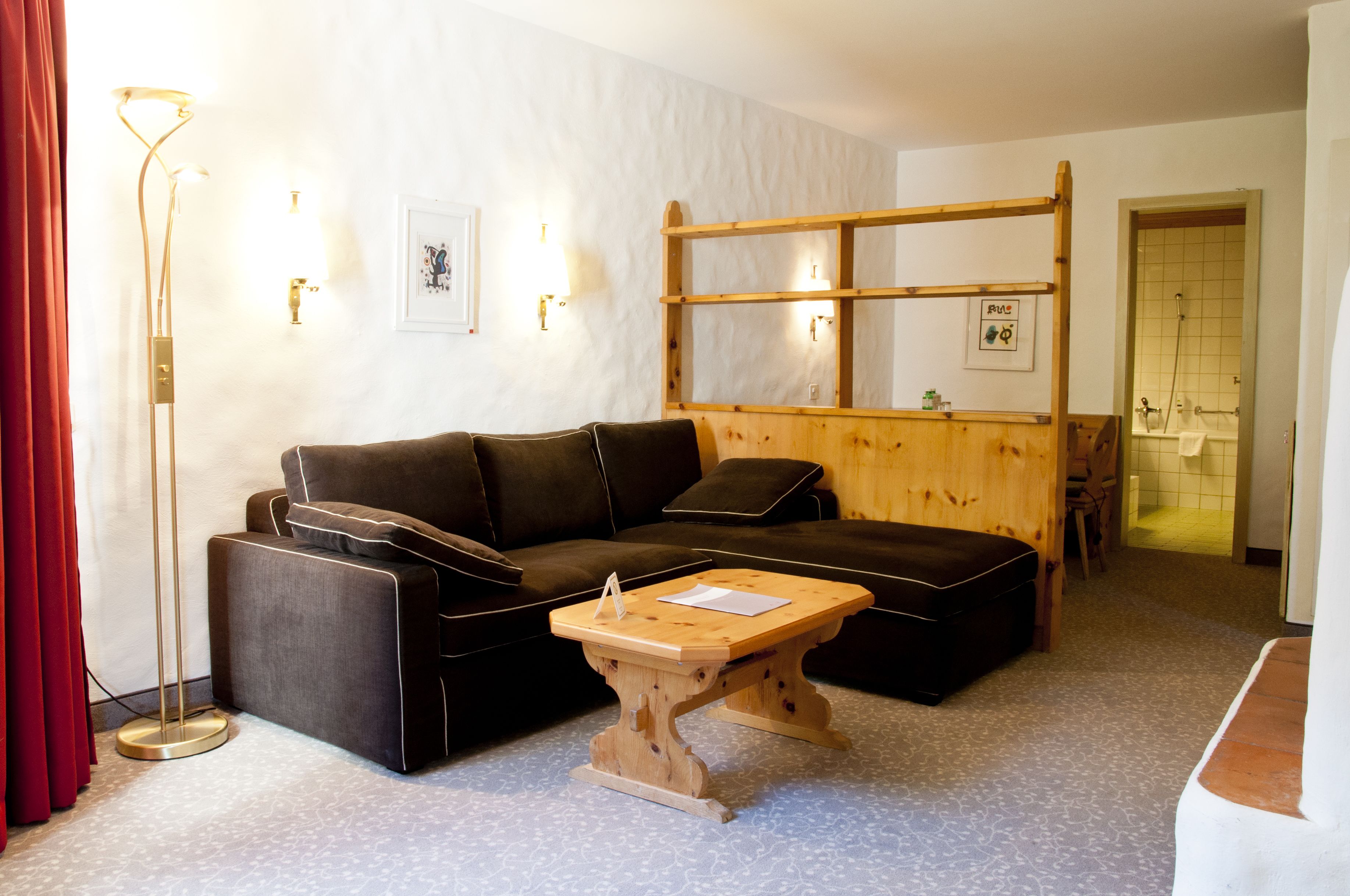 En moderne stue med en mørkebrun hjørnesofa, et træsofabord og en gulvlampe.