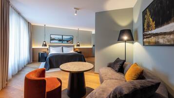 Quarto de hotel moderno com uma cama, uma mesa redonda, um sofá e um quadro na parede.