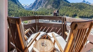 A wooden deck with a table and chairs, overlooking a mountainous landscape with a clear sky. - Hotel Rosatsch - Stammhaus (Pontresina)