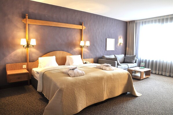 A hotel room with a large bed, a sofa, a nightstand, and a small table. - Hotel Rosatsch - Stammhaus (Pontresina)