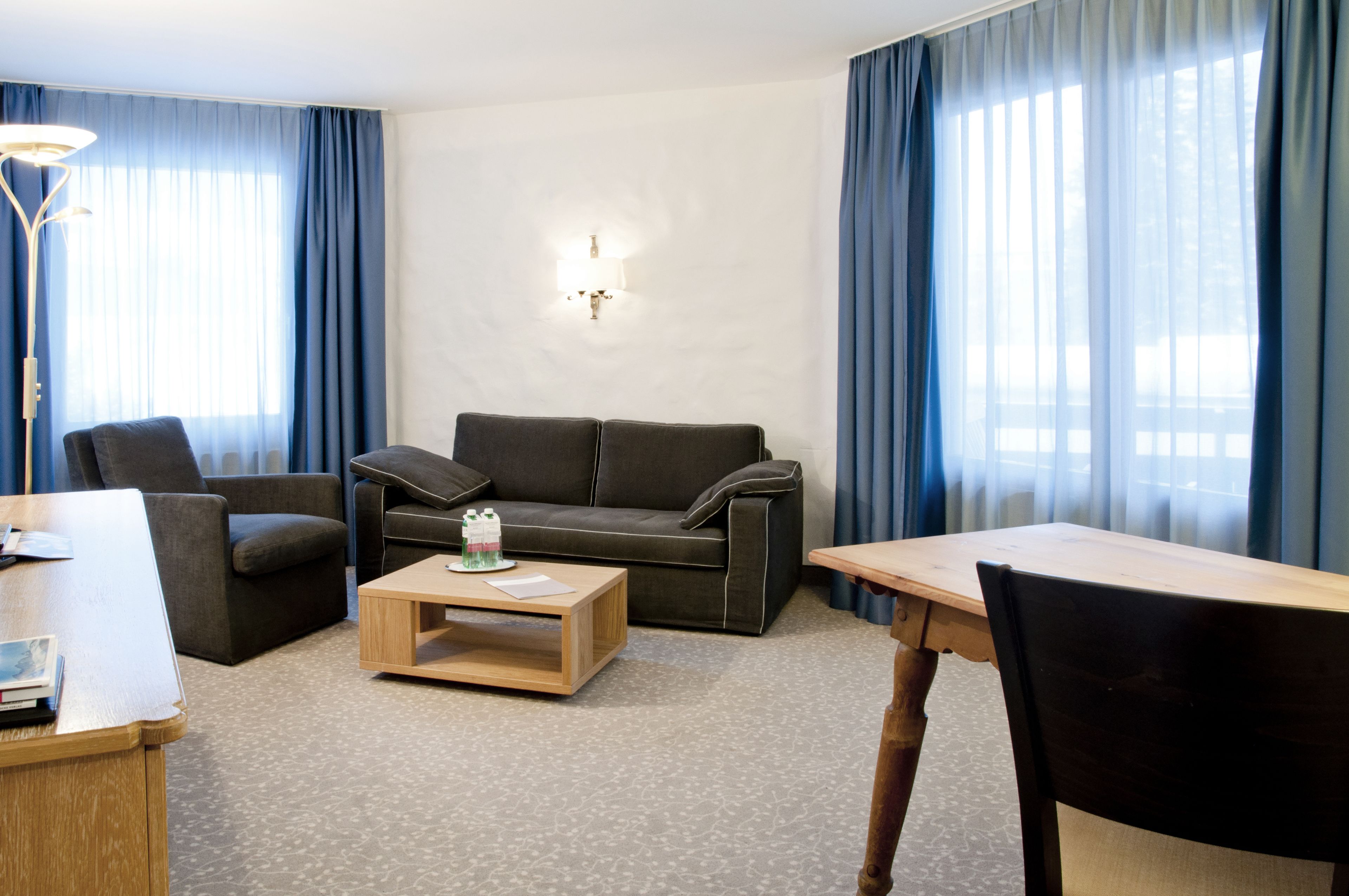 A modern living room with a sofa, armchairs, a coffee table, and a dining table.
