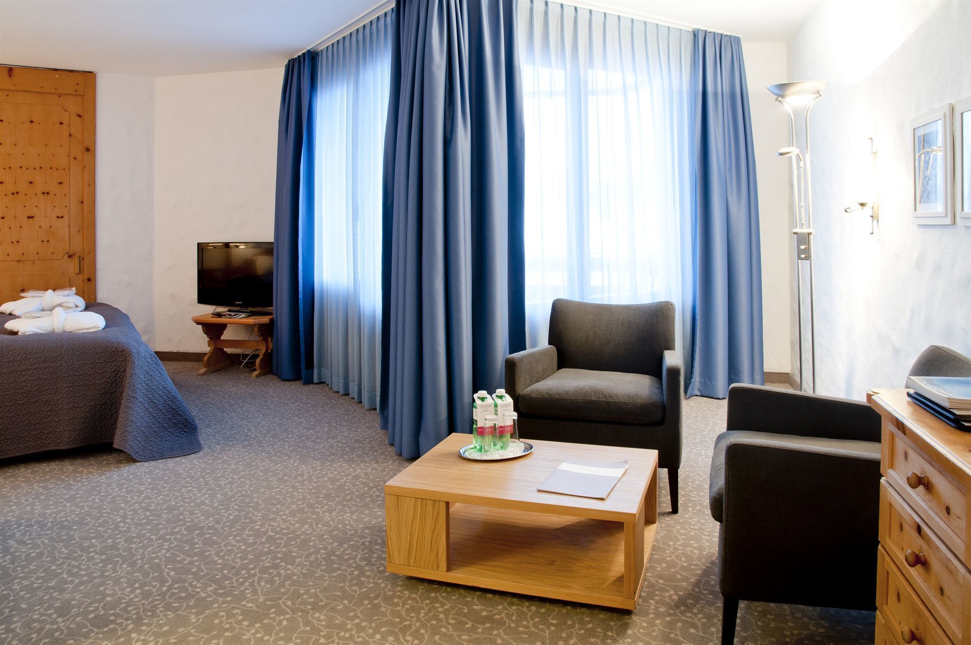 Een hotelkamer met een bed, een bureau, een stoel, een salontafel en een televisie.
