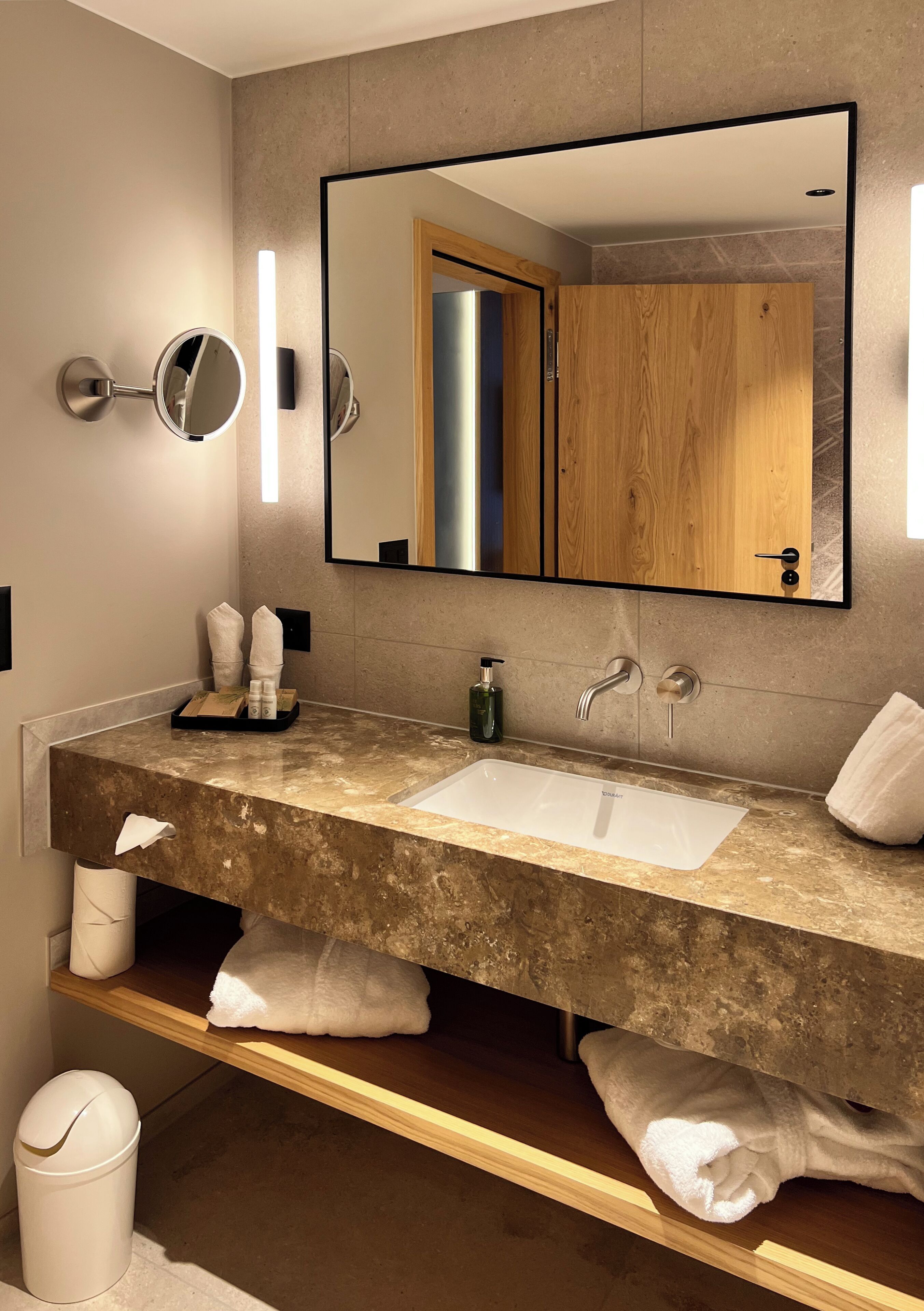 Une salle de bain moderne avec un grand miroir, un lavabo et un meuble en bois.