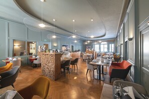 Ein geräumiges Restaurant mit hohen Decken, moderner Pendelleuchten und einer Mischung aus Holz- und Polstermöbeln.