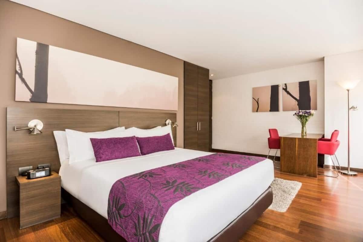 A modern hotel room with a large bed, a desk, and a chair.