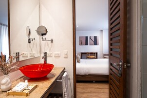 A modern bathroom with a red basin, a mirror, and a towel rack.