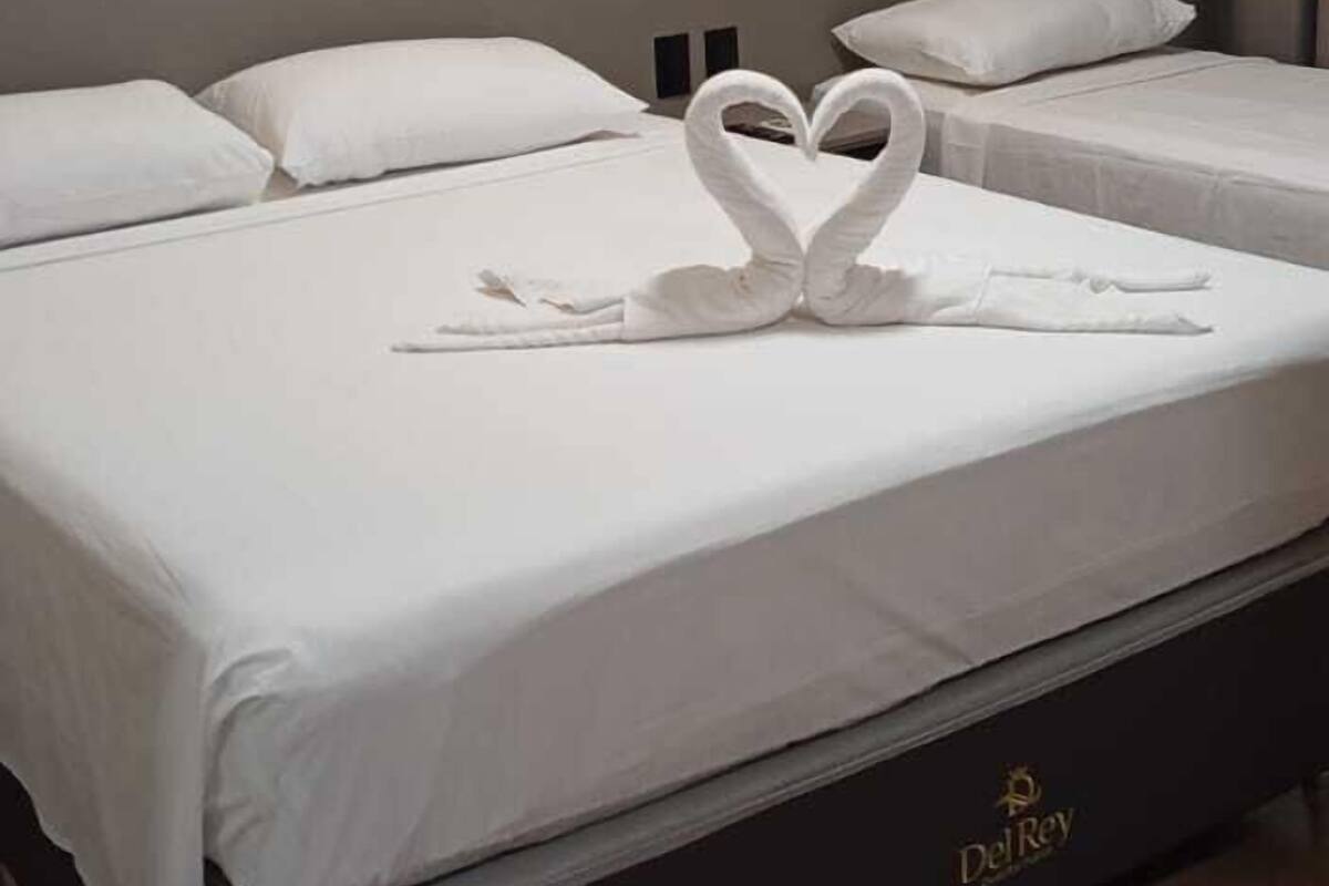 Ein Hotelzimmer mit einem großen Bett, einem mit Beleuchtung versehenen Kopfteil und einem Logo am Bettgestell.