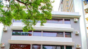 A multi-story building with a sign reading "Village Fox Hotel." There are potted plants on the ground floor and balconies with plants on the upper floors. - Hotel Village (Foz do Iguaçu)