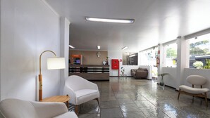 A modern lobby with a reception desk, seating area, and a large window. - Hotel Village (Foz do Iguaçu)