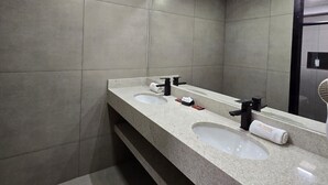 A modern bathroom with two sinks, a large mirror, and recessed ceiling lights. - Hotel Village (Foz do Iguaçu)