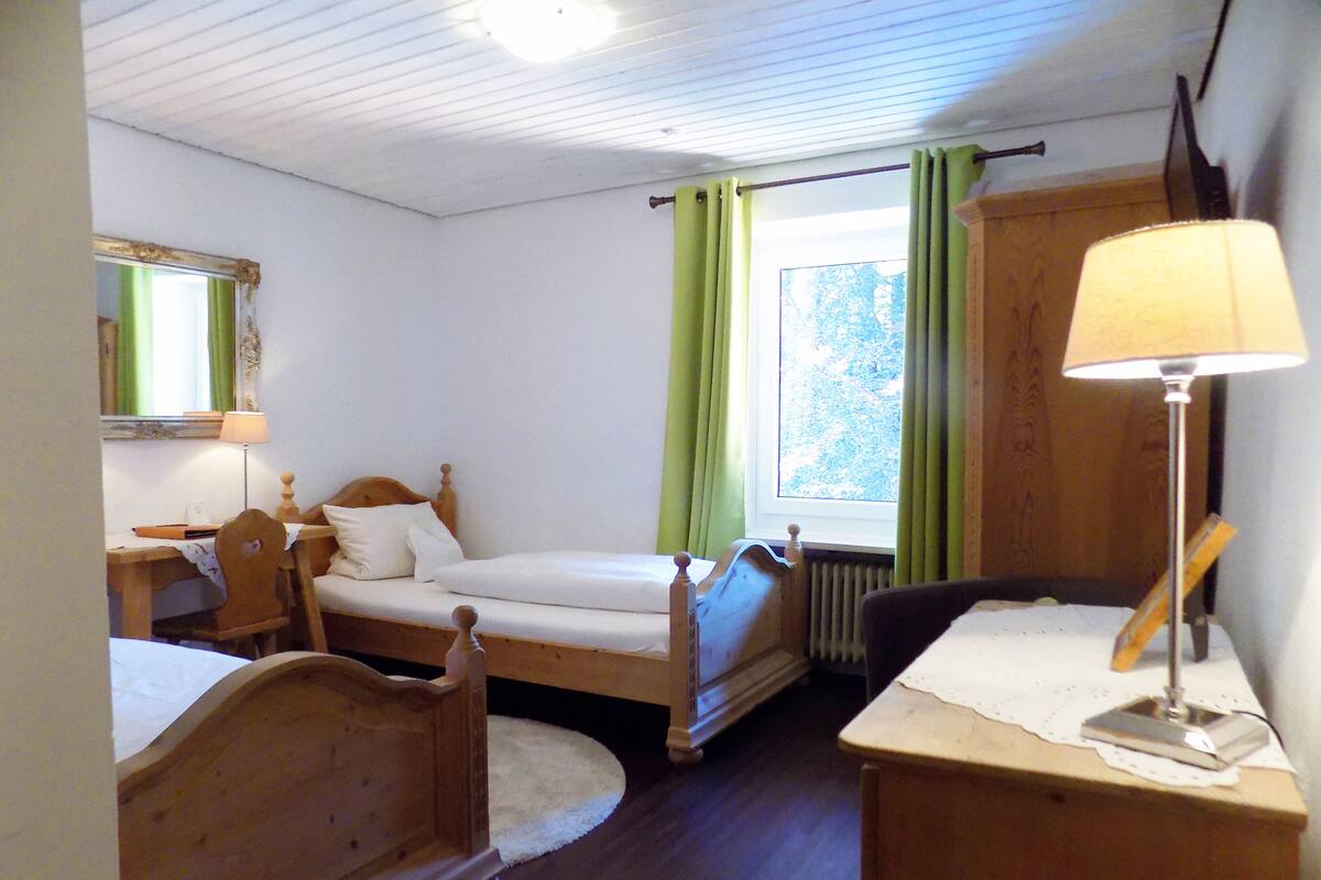Un dormitorio con una cama individual, un aparador de madera, un escritorio y una silla.