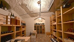 Ein Weinkeller mit Holzböden und Kisten, einer Steinwand und einer Decke mit einer Leuchte.