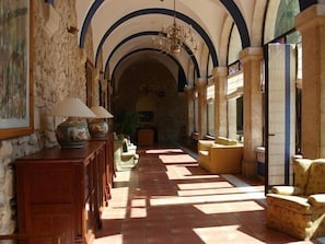 A hallway with stone walls, wooden furniture, and a chandelier.