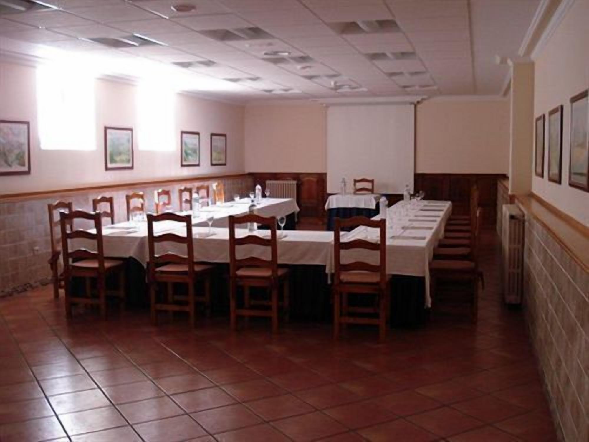 A conference room with a long table, chairs, and a projector screen.