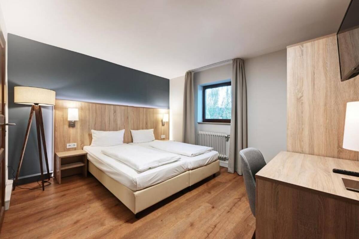 Camera d'albergo moderna con un letto grande, comodini, una scrivania e una finestra con tende.