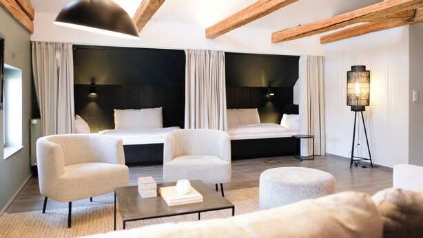 A modern hotel room with a large bed, two armchairs, a coffee table, and a floor lamp. - Weichandhof (Munich)
