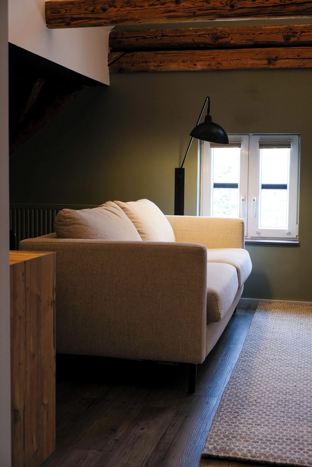 Una habitación acogedora con sofá, lámpara y ventana.
