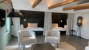 A modern hotel room with two beds, a desk, a chair, and a floor lamp. - Weichandhof (Munich)
