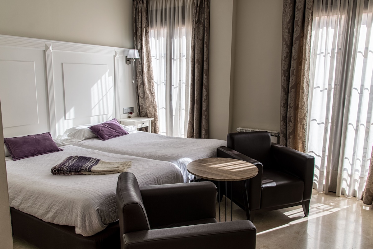 Une chambre d’hôtel avec deux lits, une petite table ronde, une chaise et une table de chevet.