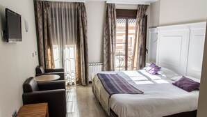 A hotel room with a bed, a sofa, a small table, and a TV. - Hotel Sevilla (Ronda)