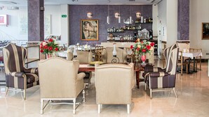 A hotel lobby with a bar area, seating arrangements, and a large painting on the wall. - Hotel Sevilla (Ronda)