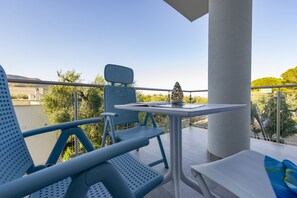 A balcony with blue chairs, a small table, and a decorative item. - Hotel Residence Torre del Porto (Mattinata)