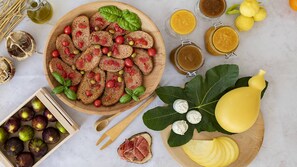 A wooden board with sliced bread topped with tomatoes and olives, surrounded by various fruits and a yellow squash. - Hotel Residence Torre del Porto (Mattinata)