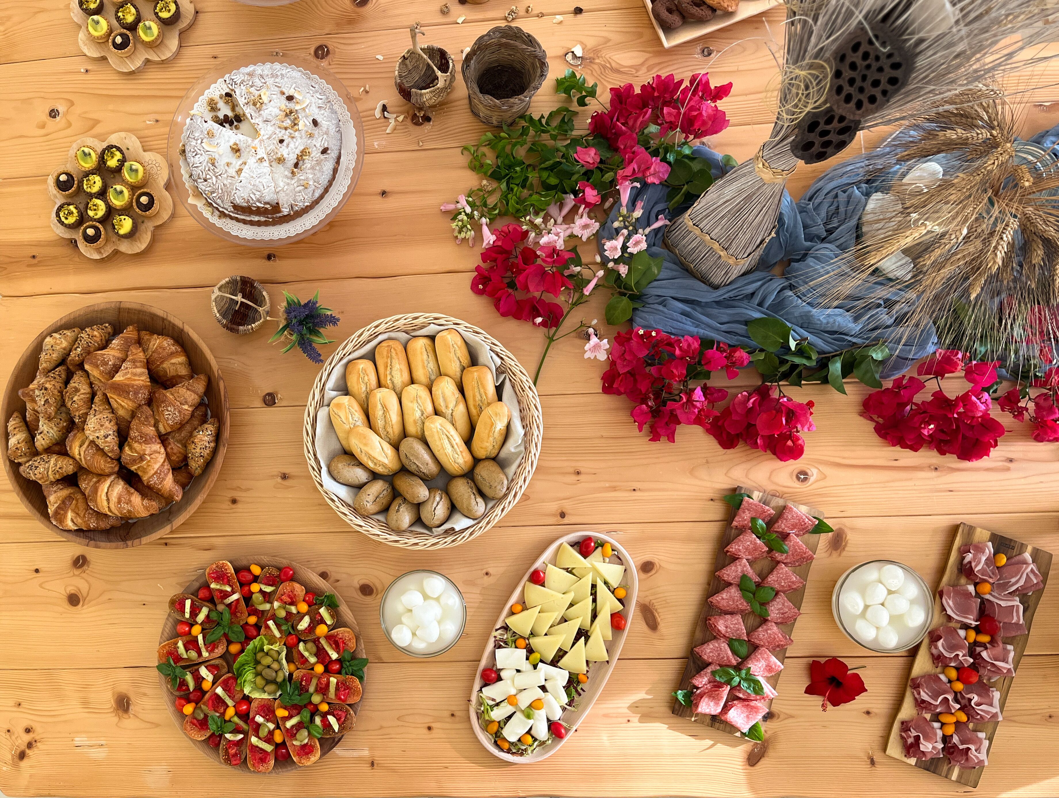A wooden table with various food items, including pastries, bread, and cheese.
