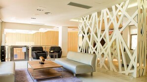 A modern hotel lobby with a sofa, a coffee table, and a decorative partition. - Hotel Melina (Benidorm)