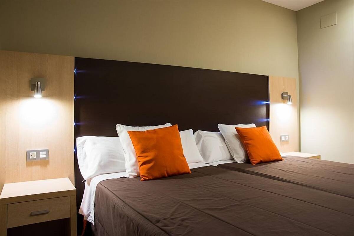 A hotel room with a large bed, two nightstands, and a modern headboard.