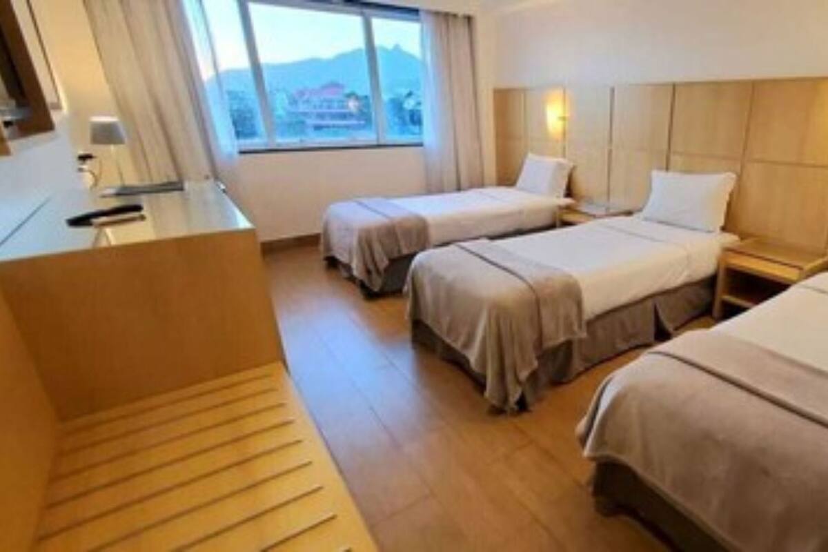 Een hotelkamer met twee bedden, een bureau en een raam met uitzicht.