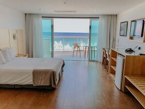 Een hotelkamer met een bed, een bureau, een stoel en uitzicht op de oceaan.