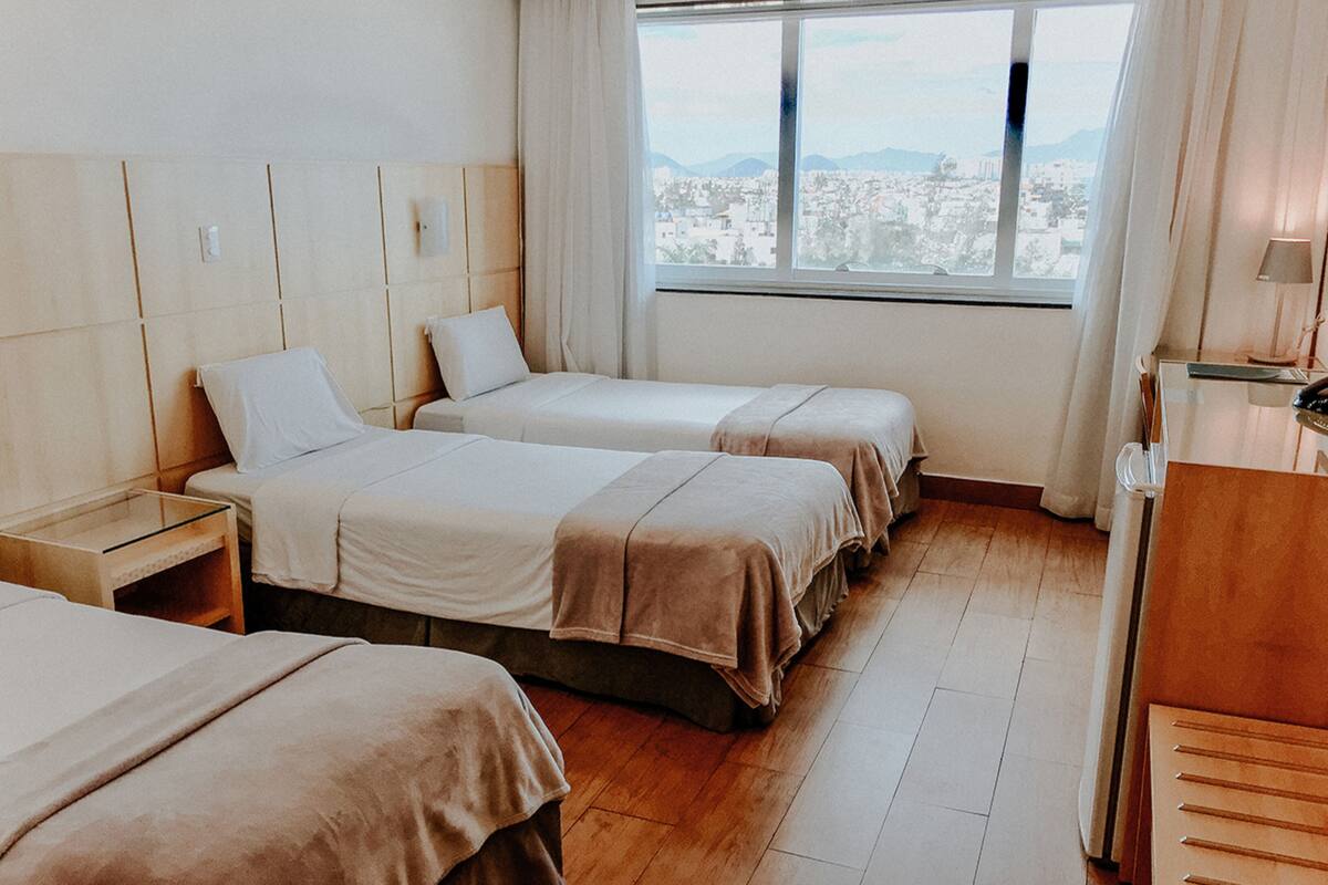 Een hotelkamer met twee bedden, een bureau en een raam met uitzicht op de stad.