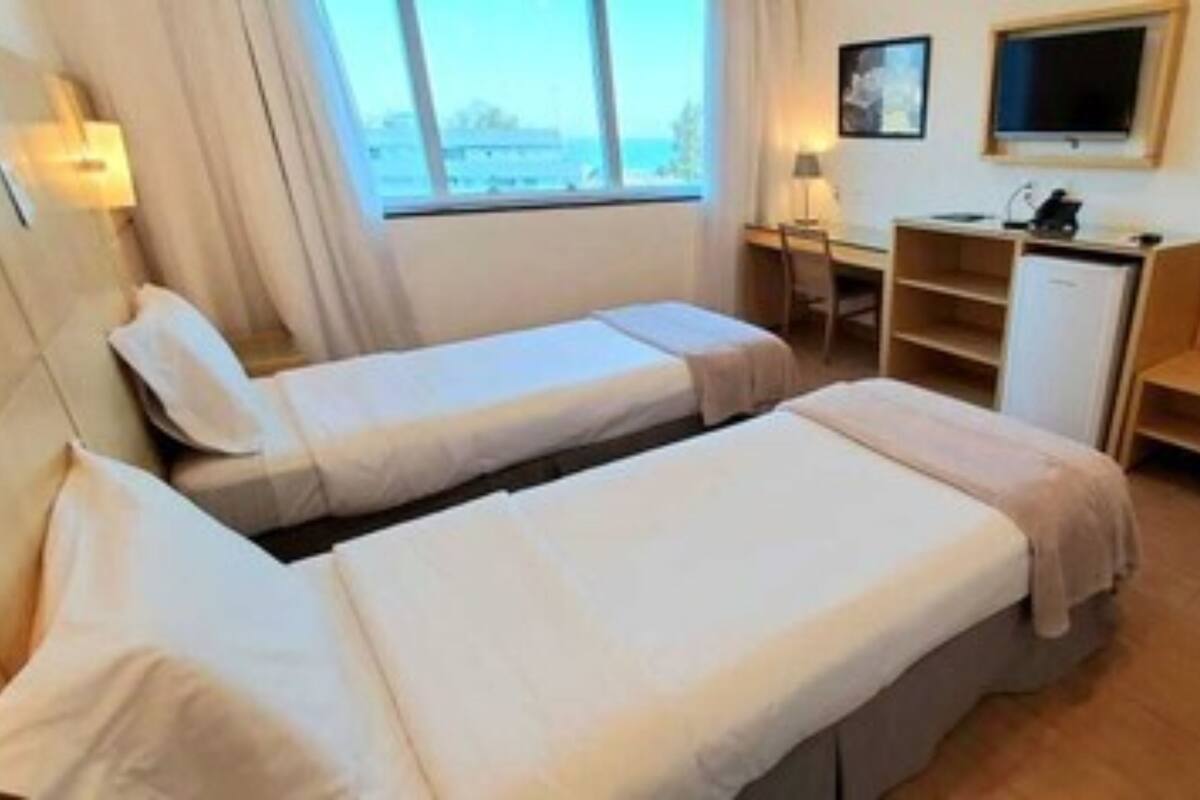 Een hotelkamer met twee eenpersoonsbedden, een bureau, een stoel, een kastje en een bank.