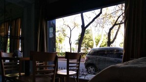 A room with a large window, wooden chairs, and a view of a street outside. - Aldeano II (Buenos Aires)