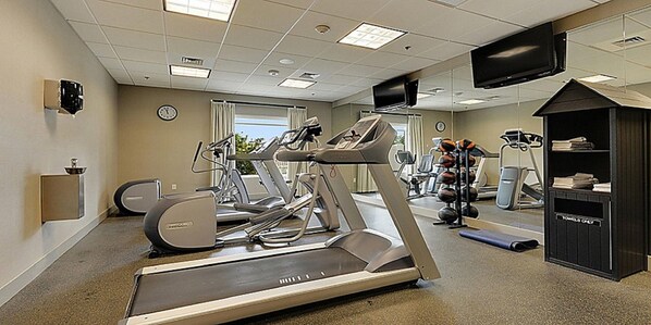 A fitness center with treadmills, elliptical machines, and a weight station.