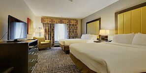 A hotel room with two beds, a television, a desk with a chair, and a patterned carpet.
