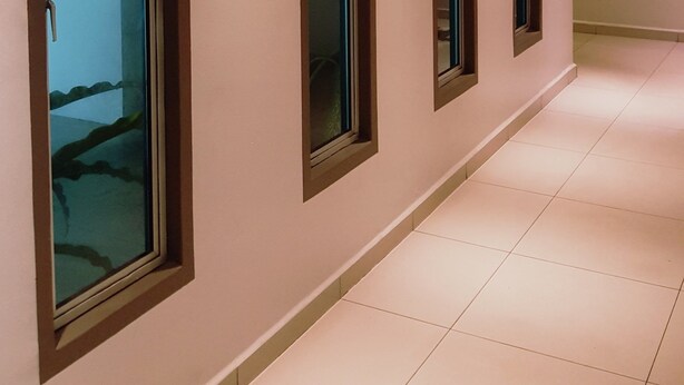 A corridor with four windows, recessed lighting, and a tiled floor.