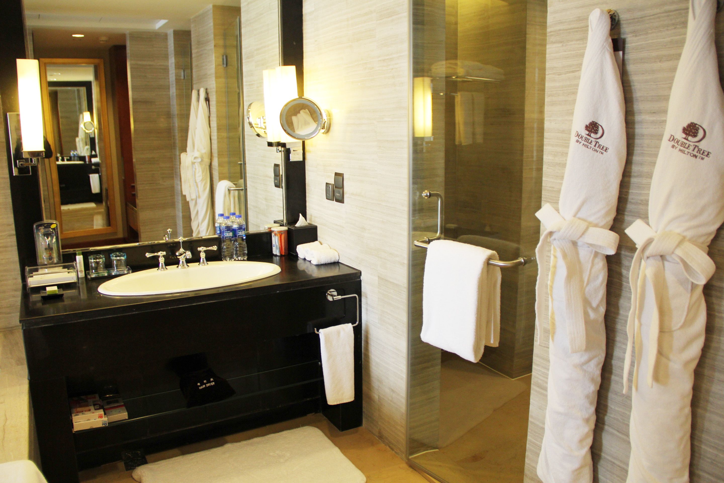 Un baño moderno con un espejo grande, un lavamanos y una cabina de ducha de vidrio.